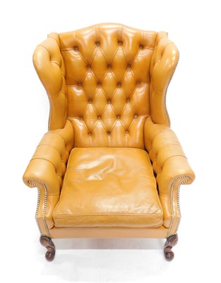 Lot 42 - A tan leather wing back chair in George III...