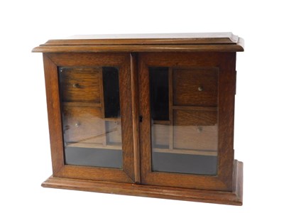 Lot 915 - An Edwardian oak tobacco cabinet, the hinged...